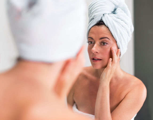 Beautiful mature lady with a towel looking in the mirror