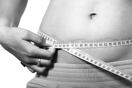 Woman measuring waist with tape measure.